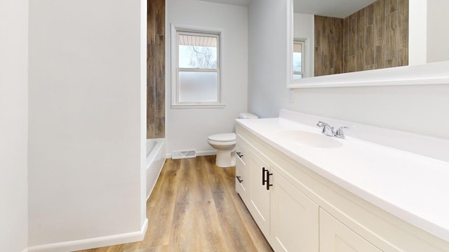 full bath with vanity, wood finished floors, visible vents, baseboards, and toilet