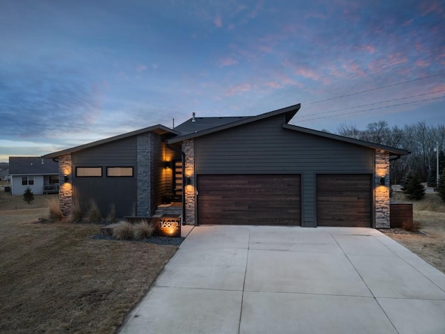 modern home featuring stone siding, concrete driveway, and an attached garage