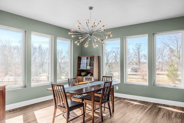 dining area featuring a chandelier, light wood-type flooring, visible vents, and baseboards