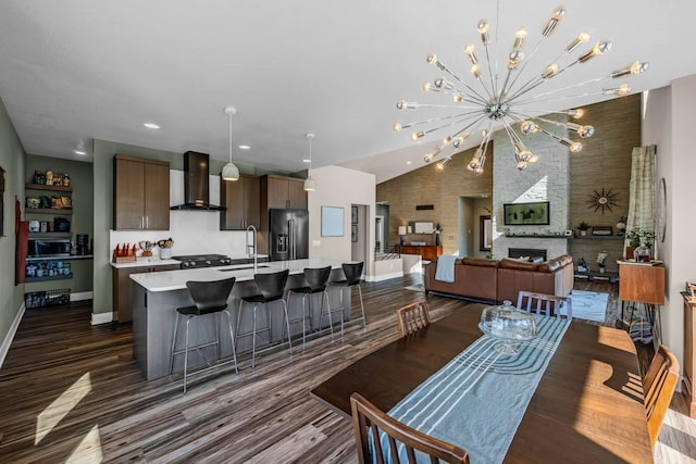 dining room with dark wood-style flooring, a fireplace, an inviting chandelier, high vaulted ceiling, and baseboards