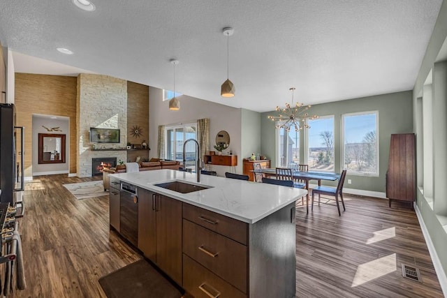 kitchen with a textured ceiling, a fireplace, a sink, open floor plan, and a center island with sink