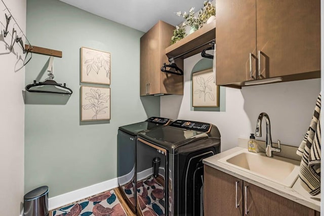 laundry room with cabinet space, baseboards, separate washer and dryer, and a sink