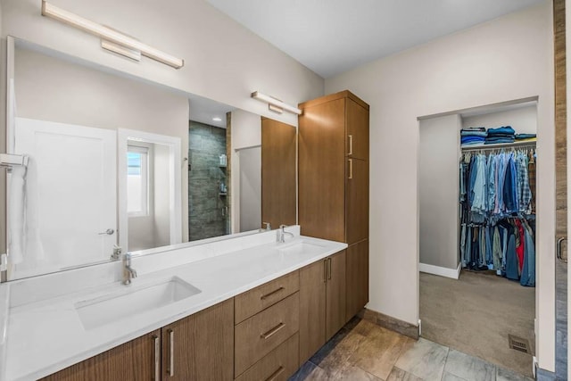 full bathroom with double vanity, a shower stall, a spacious closet, and a sink