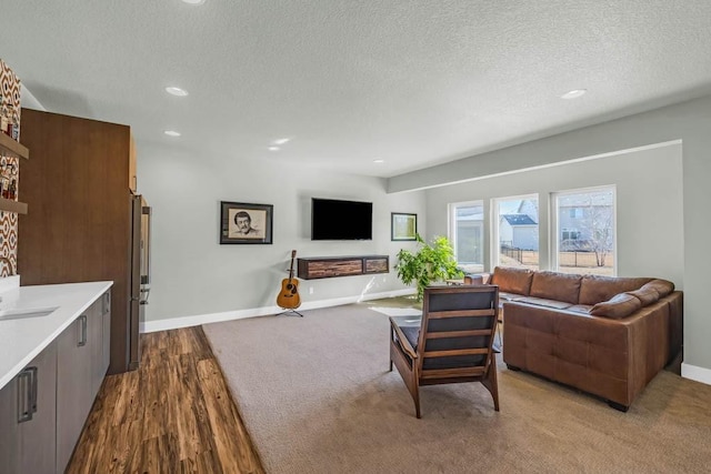 living room featuring a textured ceiling, light wood-style floors, recessed lighting, and baseboards