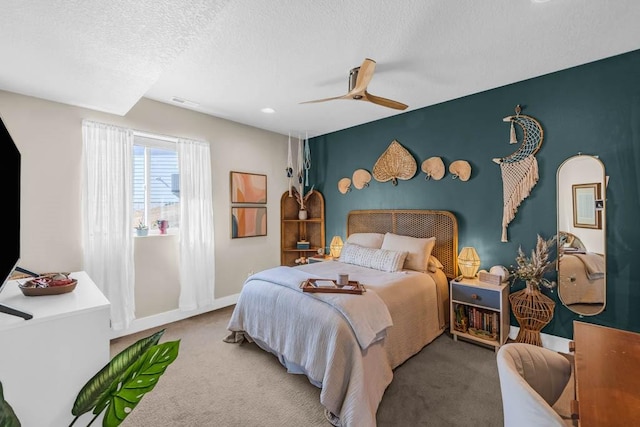 carpeted bedroom featuring ceiling fan, an accent wall, baseboards, and a textured ceiling