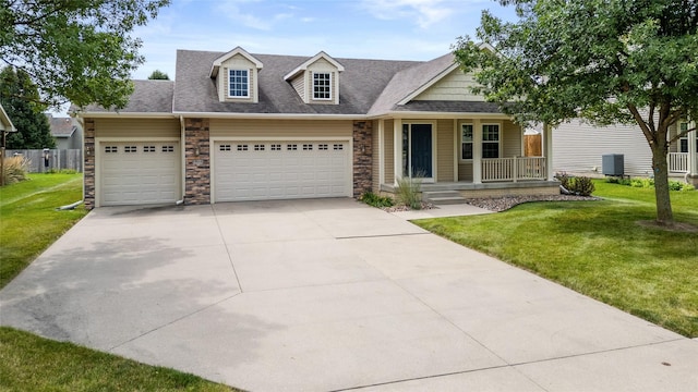 view of front facade featuring covered porch, a shingled roof, stone siding, driveway, and a front lawn