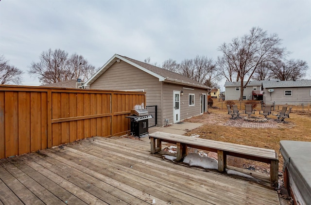 wooden terrace with an outdoor fire pit, a grill, and fence