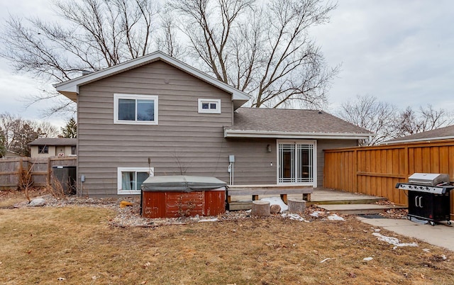 back of house featuring a hot tub, fence, a deck, and roof with shingles