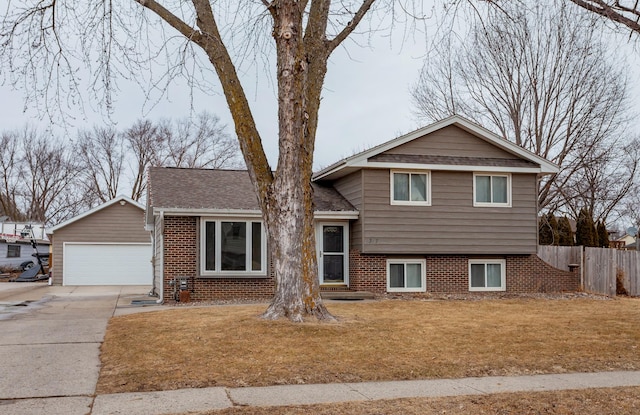 tri-level home with roof with shingles, brick siding, a front lawn, and fence