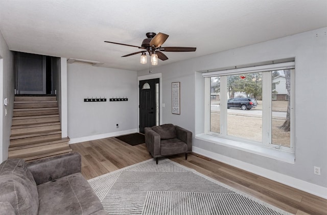 living area with stairway, baseboards, and wood finished floors