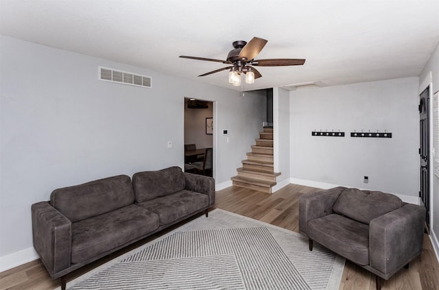 living area featuring stairway, baseboards, visible vents, and wood finished floors