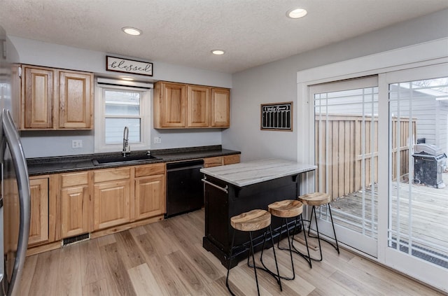 kitchen with a sink, visible vents, black dishwasher, light wood-type flooring, and freestanding refrigerator