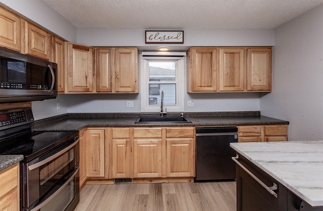 kitchen with black dishwasher, range with two ovens, a textured ceiling, light wood-type flooring, and a sink