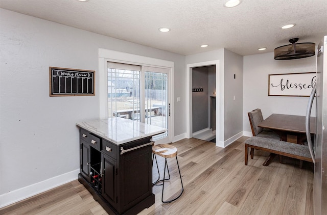 dining area featuring recessed lighting, light wood-style flooring, baseboards, and a textured ceiling