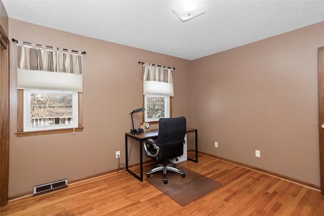 office space featuring light wood-style floors, baseboards, and visible vents