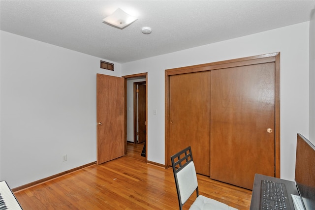 unfurnished bedroom with a closet, light wood-type flooring, visible vents, and baseboards