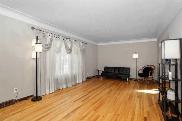 living area with light wood-style floors, baseboards, and visible vents