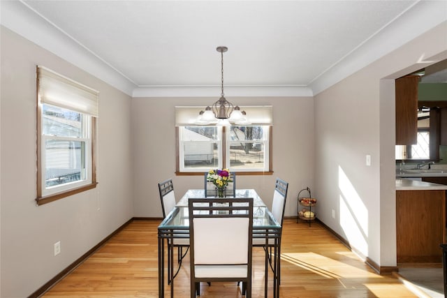 dining area featuring light wood-type flooring, baseboards, and an inviting chandelier