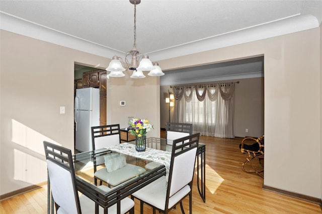 dining space featuring baseboards, light wood-style flooring, and an inviting chandelier