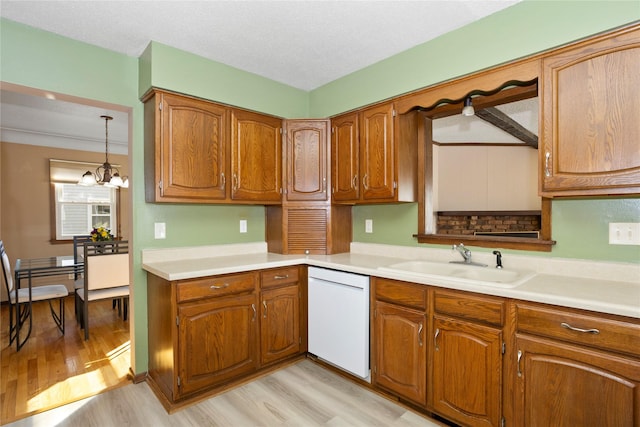 kitchen with light wood finished floors, white dishwasher, a sink, and brown cabinets