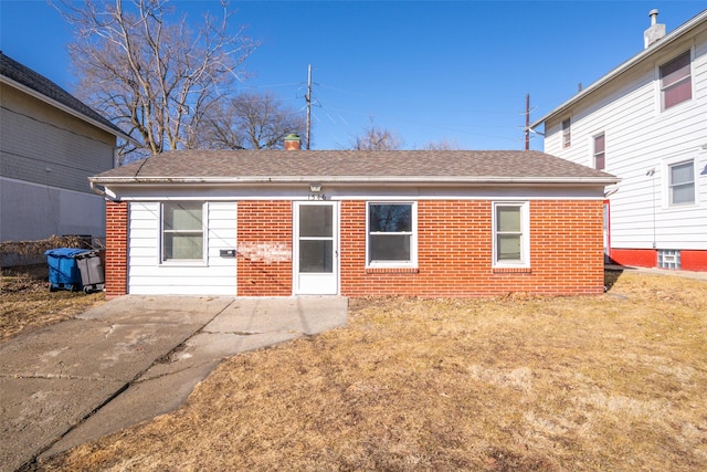 back of house with roof with shingles, a lawn, a patio, and brick siding