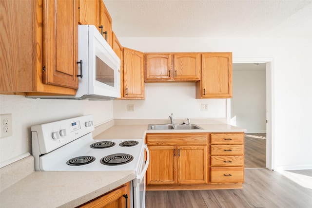 kitchen featuring light countertops, white appliances, a sink, and light wood-style flooring