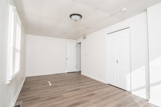 unfurnished bedroom with visible vents, wood finished floors, a paneled ceiling, and baseboards