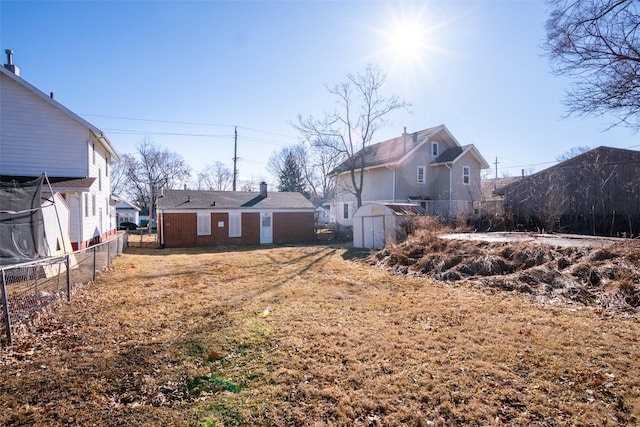 view of yard with fence, a storage unit, and an outbuilding