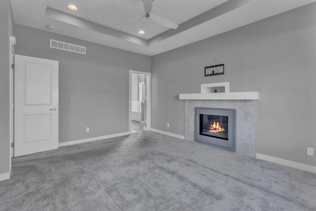 unfurnished living room with baseboards, visible vents, a tray ceiling, and carpet flooring