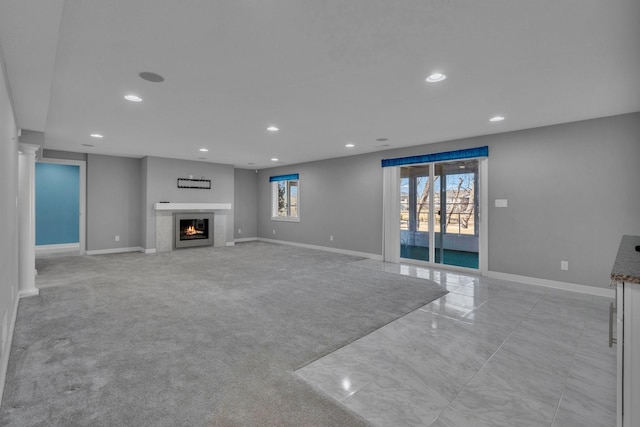 unfurnished living room with recessed lighting, a lit fireplace, and baseboards