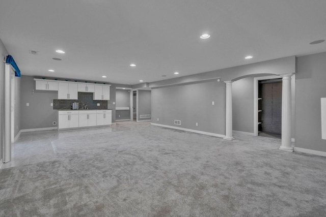 unfurnished living room featuring recessed lighting, light colored carpet, decorative columns, and baseboards