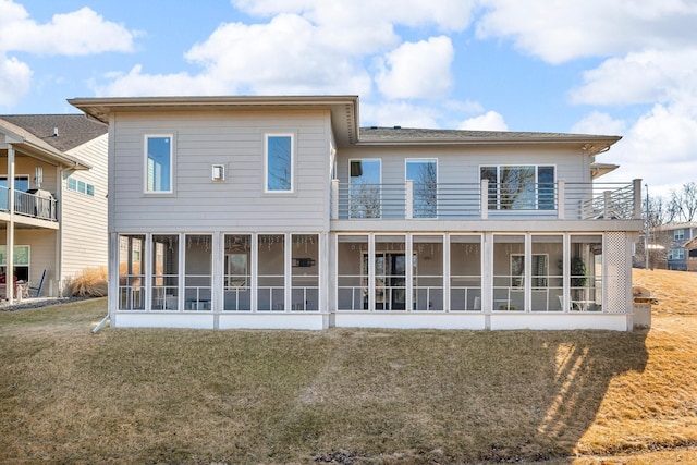 back of property with a sunroom, a yard, and a balcony