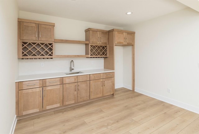 kitchen featuring open shelves, light countertops, light wood-style flooring, a sink, and baseboards