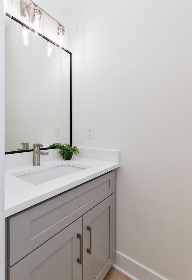 bathroom featuring baseboards, wood finished floors, and vanity