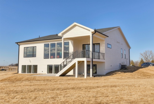 rear view of property featuring stairs, central AC, and a yard