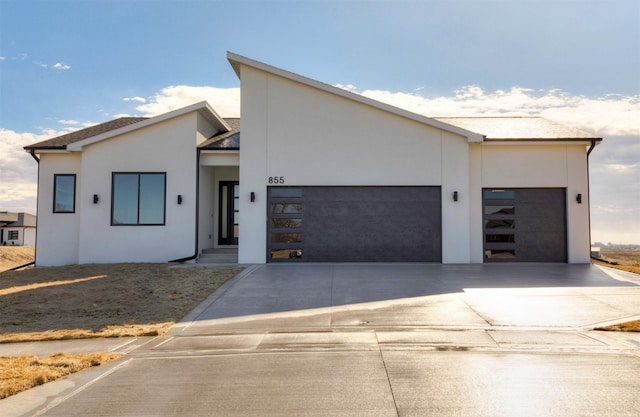 contemporary home featuring an attached garage, concrete driveway, and stucco siding