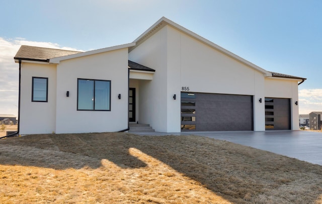 contemporary house with a garage, concrete driveway, and stucco siding