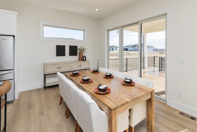 dining space with light wood finished floors, visible vents, and a wealth of natural light