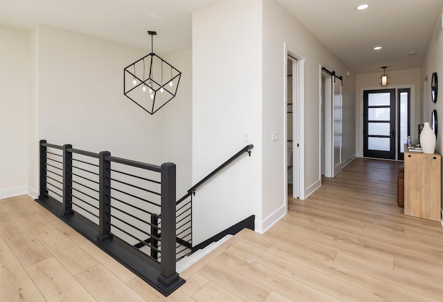 corridor with a barn door, recessed lighting, an upstairs landing, baseboards, and light wood-style floors