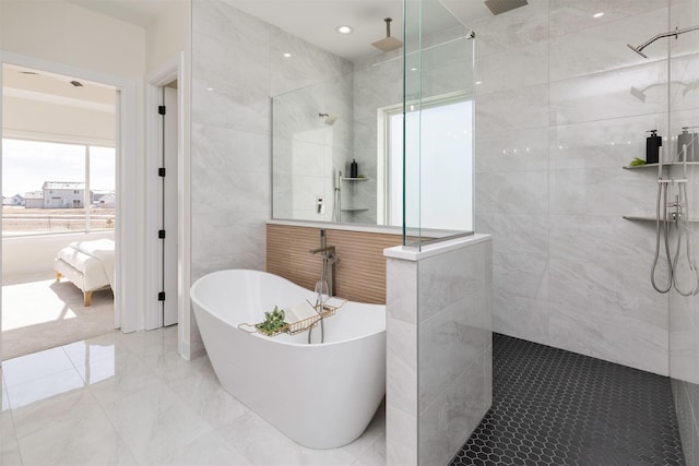 ensuite bathroom featuring connected bathroom, a soaking tub, marble finish floor, a walk in shower, and tile walls