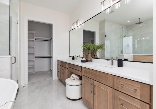 full bathroom with double vanity, a stall shower, a walk in closet, a freestanding tub, and a sink