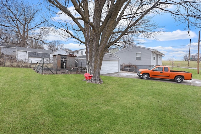 view of yard with a detached garage, fence, and an outbuilding