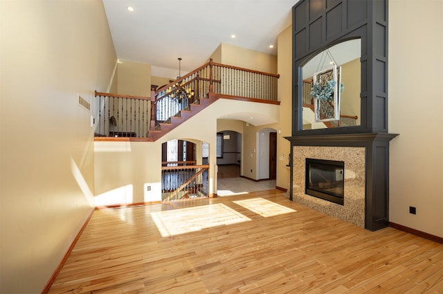 unfurnished living room with arched walkways, a fireplace, visible vents, baseboards, and hardwood / wood-style floors