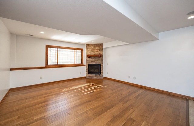 unfurnished living room with visible vents, a fireplace, baseboards, and hardwood / wood-style flooring