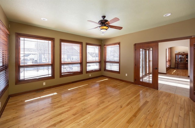 spare room with arched walkways, ceiling fan, recessed lighting, baseboards, and light wood-type flooring