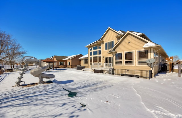 snow covered house featuring fence