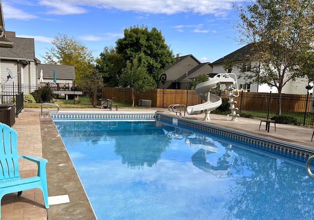 view of pool with a patio area, a fenced in pool, fence, and a water slide