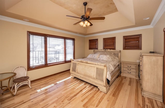 bedroom with ceiling fan, baseboards, a tray ceiling, light wood finished floors, and crown molding