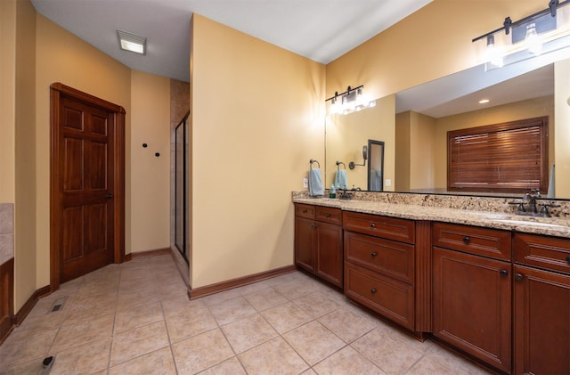 full bathroom with double vanity, a stall shower, a sink, tile patterned flooring, and baseboards