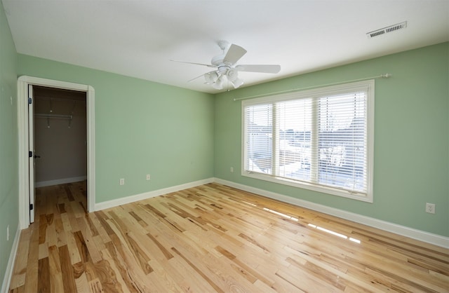 spare room featuring light wood-style floors, visible vents, ceiling fan, and baseboards